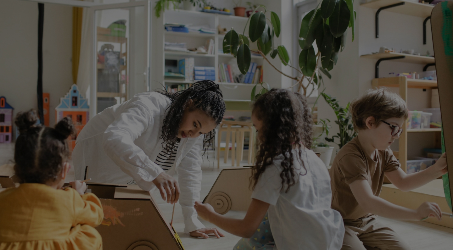 Woman playing with three young children on floor of living area