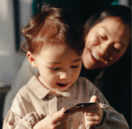 Toddler on mother's lap holding item looking in amazement